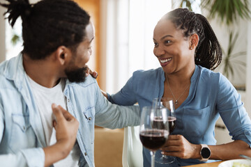 Young African-American couple talking while drinking red wine at home