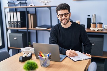 Young arab man business worker writing on clipboard working at office