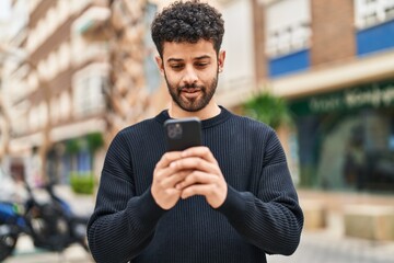 Young arab man smiling confident using smartphone at street