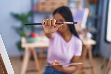 African american woman artist looking paintbrush at art studio