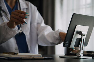 Young doctor with diary sitting at desk in medical clinic