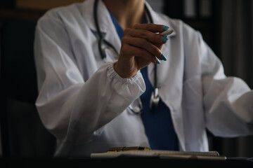 Young doctor with diary sitting at desk in medical clinic