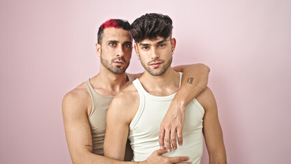 Two men couple hugging each other with relaxed expression over isolated pink background
