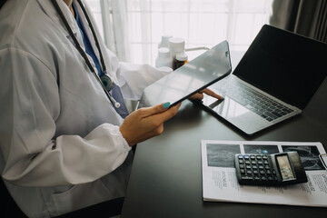 Young doctor with diary sitting at desk in medical clinic