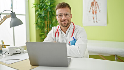 Young man doctor using laptop working at clinic