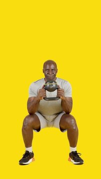 Sportive african man doing globet squat with kettlebell