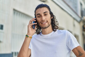 Young hispanic man smiling confident talking on the smartphone at street