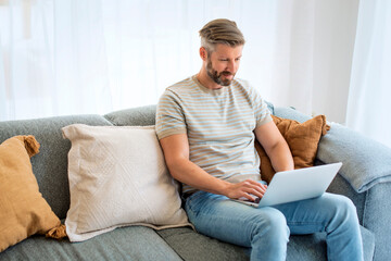 Confident businessman sitting at home and using laptop for work