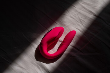 Pink silicone vibrator on a white sheet.