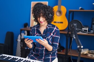 Young middle east woman artist singing song using touchpad at music studio