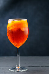 Aperol Spritz cocktail on dark wooden planks. Cocktail Aperol Spritz with oranges and ice cubes in glass. Traditional italian aperitif cocktail