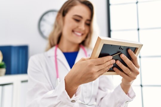 Young woman wearing doctor uniform looking photo at clinic