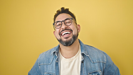 Young latin man smiling confident standing over isolated yellow background