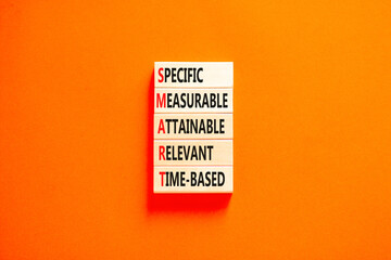 SMART symbol. Concept words SMART specific measurable attainable relevant time-based on block. Beautiful orange background. Business SMART specific measurable attainable relevant time-based concept.
