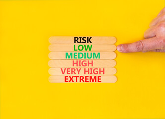 Time to low risk symbol. Concept word Risk low medium high very high extreme on wooden sticks. Businessman hand. Beautiful yellow background. Business time to low risk concept. Copy space.