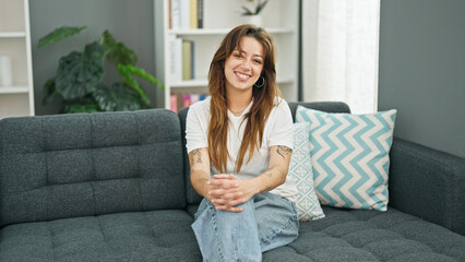 Young beautiful hispanic woman smiling confident sitting on sofa at home