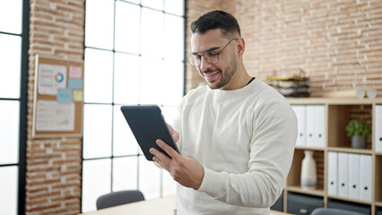 Young hispanic man business worker smiling confident using touchpad at office