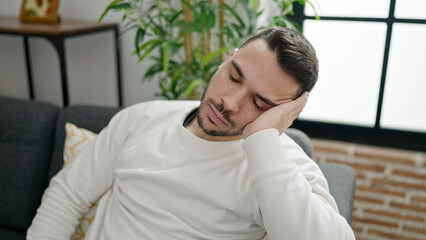 Young hispanic man sitting on sofa sleeping at home