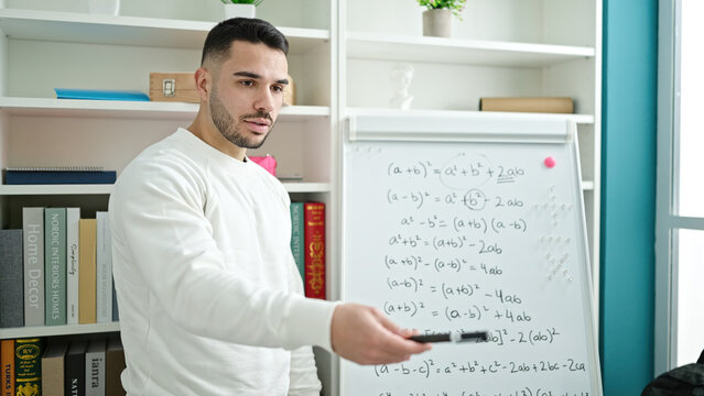 Young hispanic man teacher teaching maths lesson at library university
