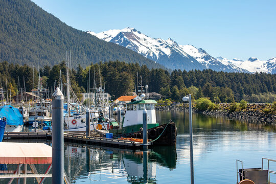 fishing boats moored in the docks in Sitka Alaska with scenic snowcapped mountains in the background 