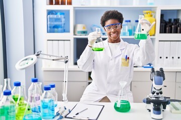 African american woman wearing scientist uniform measuring liquid at laboratory