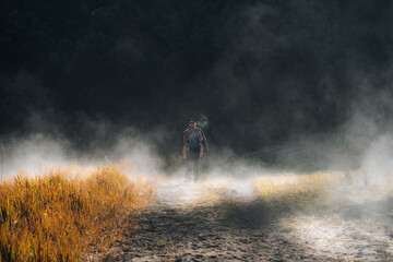Young man meets the sunrise at the Bromo Tengger Semeru National Park on the Java Island, Indonesia. He enjoys magnificent view on the Bromo or Gunung Bromo on Indonesian, Semeru and other volcanoes