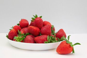 A white bowl filled with ripe straberries