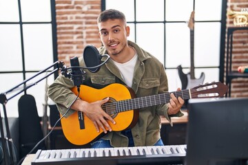 Young hispanic man musician singing song playing classical guitar at music studio