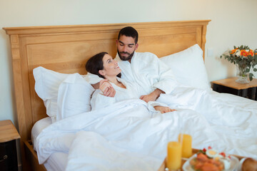 Loving Couple Hugging During Breakfast In Bed At Hotel Indoors