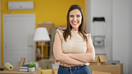 Young beautiful hispanic woman smiling confident standing with arms crossed gesture at new home