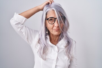 Middle age woman with tattoos wearing glasses standing over white background confuse and wonder about question. uncertain with doubt, thinking with hand on head. pensive concept.