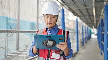 Middle age grey-haired woman builder using touchpad at street