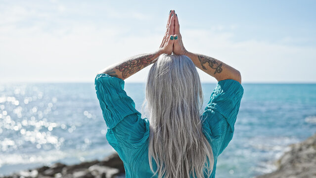 Middle age grey-haired woman doing yoga exercise at seaside