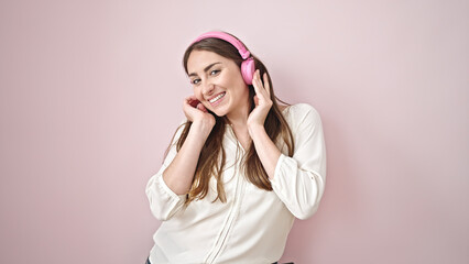 Young beautiful hispanic woman listening to music and dancing over isolated pink background