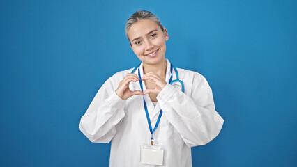 Young beautiful hispanic woman doctor smiling doing heart gesture with hands over isolated blue background