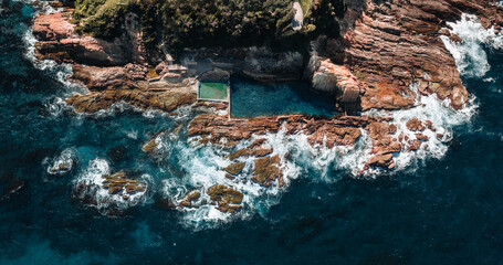 Aerial drone view of Blue Pool in Bermagui during sunrise sunset with blue sky and reflection. New South Wales, Australia