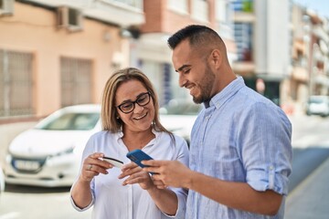 Man and woman mother and daugther using smartphone and credit card at street