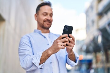 Young caucasian man smiling confident using smartphone at street