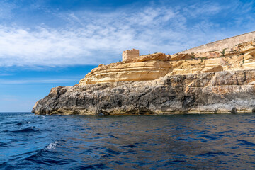 Fototapeta na wymiar Malta, near the habour of Wied iz-Zurrieq, an old watchtower seen from the seaside when coming back from the blue grottos.
