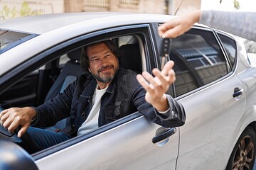 Fototapeta na wymiar Middle age man smiling confident holding key of new car at street