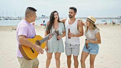 Group of people playing guitar drinking beer singing song at beach