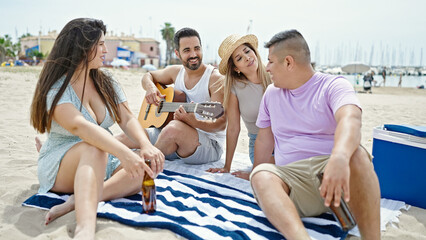Group of people playing guitar drinking beer singing song at beach