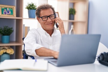Middle age man talking on smartphone sitting on wheelchair teleworking at home