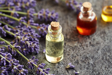 A bottle of essential oil with blooming lavender twigs