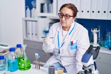 Fototapeta premium Senior woman scientist holding tweezer at laboratory