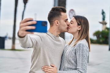 Man and woman couple make selfie by smartphone kissing at street