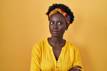 African young woman wearing african turban smiling looking to the side and staring away thinking.