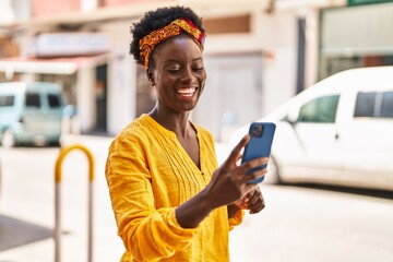 Young african american woman smiling confident using smartphone at street