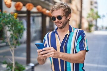 Young man tourist smiling confident using smartphone at street