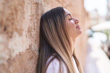 Young beautiful hispanic woman breathing with closed eyes at street